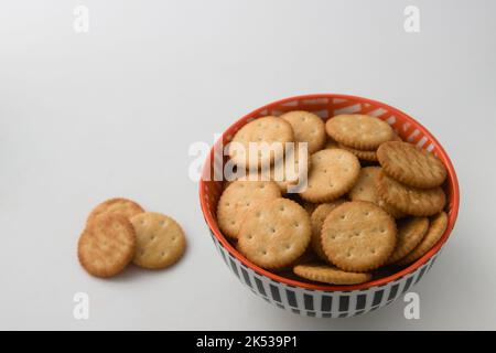 Nahaufnahme einer Schüssel mit Kräckern isoliert neben einigen Kräckern auf dem weißen Hintergrund, Bild mit Kopierraum Stockfoto