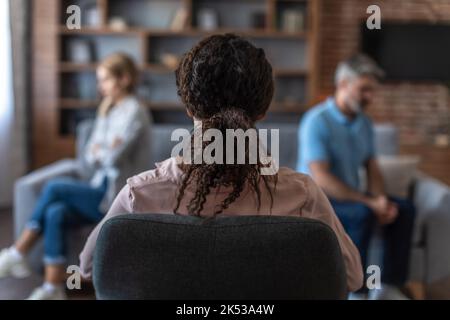 Der junge afroamerikanische Arzt berät Erwachsene europäische Paare, ignoriert sich gegenseitig, spricht über Beziehungsprobleme Stockfoto