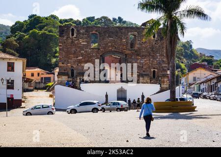 Frau, die am Praça Delfim Moreira vor der Igreja de Nossa Senhora do Rosário dos Pretos da Barra in Sabará, Minas Gerais, Brasilien, spazieren geht. Stockfoto