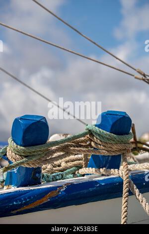 Seile mit maritimem Thema, die um hölzerne Schiffspoller auf einem alten traditionellen Holzschiff oder -Boot gebunden sind. Stockfoto