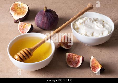 Schneiden Sie frische Feigen, Honig und Frischkäse auf dem Tisch. Stockfoto