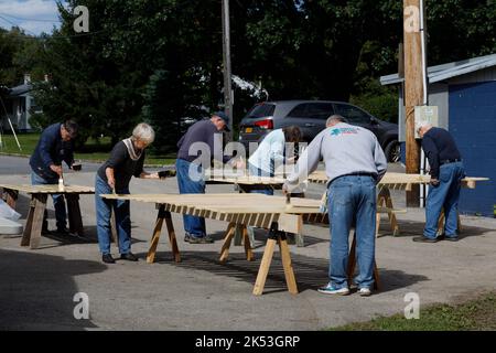 St. Johnsville, Montgomery County, New York: Freiwillige malen Holzlatten während der Reparatur der Tribüne auf dem Gemeinschaftsballfeld. Stockfoto