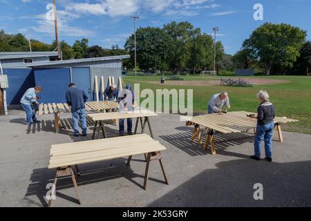 St. Johnsville, Montgomery County, New York: Freiwillige malen Holzlatten während der Reparatur der Tribüne auf dem Gemeinschaftsballfeld. Stockfoto