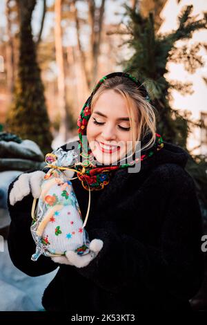 Schöne junge Frau in einem nationalen ukrainischen Kopftuch hält einen Schneemann Stockfoto