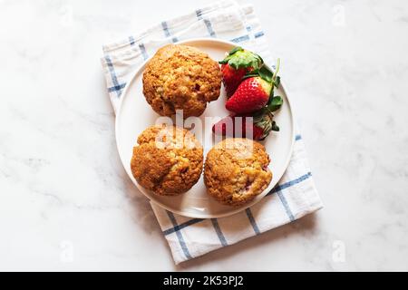 Erdbeermuffins auf einem Teller auf Marmorboden serviert. Draufsicht. Stockfoto