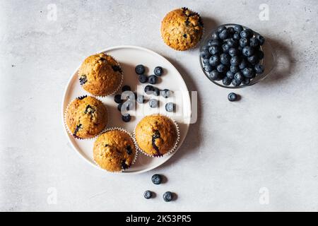 Heidelbeer-Muffins werden auf einem Teller auf Marmorboden serviert. Draufsicht. Stockfoto