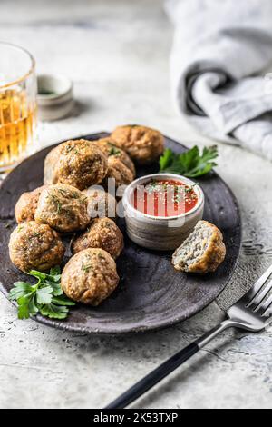 Cibriki Kartoffelfritter aus geriebenen Kartoffeln in Form von Kugeln. Traditionelle weißrussische Küche, serviert mit Sauce, Kräutern und Besteck in modernem Stil Stockfoto