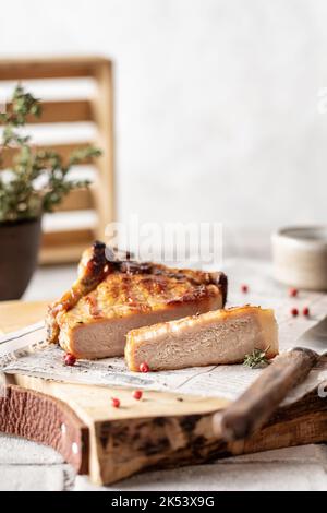 Gegrilltes Schweinesteak in Scheiben geschnitten aus nächster Nähe auf einem hölzernen Servierbrett mit Kräutern und Gewürzen im rustikalen Stil für Menü, Rezept Stockfoto