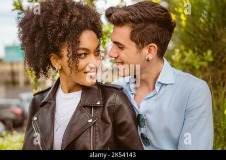 Multiethnisches Paar, mit afroamerikanischer Frau und kaukasischem Mann, die einander in die Augen schauen - romantische Menschen und diversisterer Lebensstil concep Stockfoto