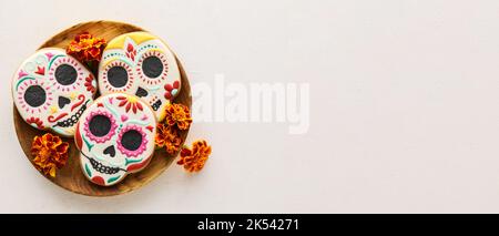 Holztablett mit leckeren Cookies in Form von Totenkopf für den Tag der Toten in Mexiko (El Dia de Muertos) auf hellem Hintergrund mit Platz für Text Stockfoto