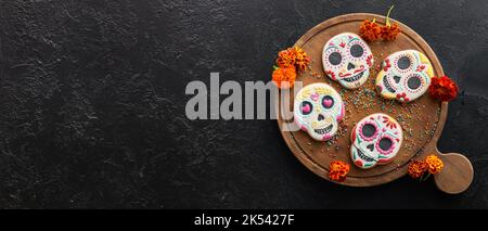 Holzbrett mit leckeren Cookies in Schädelform für Mexikos Tag der Toten (El Dia de Muertos) auf dunklem Hintergrund mit Platz für Text Stockfoto