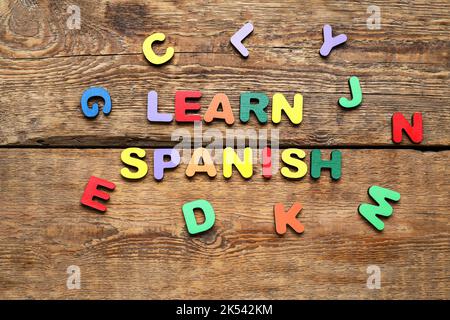 Text SPANISCH LERNEN und Buchstaben auf Holzhintergrund Stockfoto
