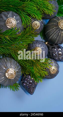 weihnachtsmockup mit grauen Kugeln und grünen Tannenzweigen auf blauem Hintergrund.Festliches Mockup in Grautönen in minimalistischem Stil Stockfoto