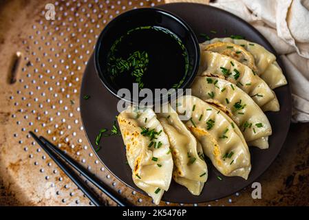 Hausgemachte, frittierte asiatische Potsticker-Vorspeise. Gyzo Asiatische Schweinepudding mit Sojasauce. Knödel auf einem Teller. Stockfoto