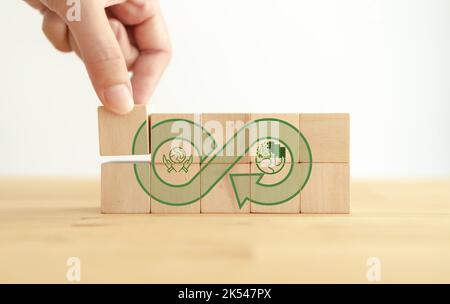 Green Eco Unendlichkeit, Netto Null, Kreislaufwirtschaft, erneuerbare Energie und Save World Konzept. Nachhaltige Entwicklung. Hand setzt Holzwürfel mit grünem e Stockfoto