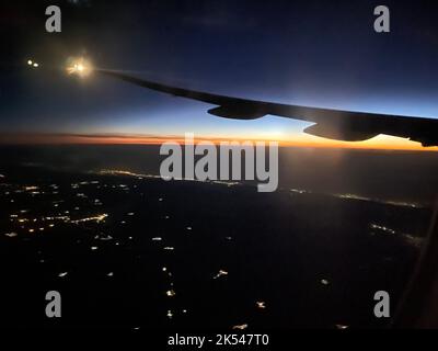 Flugzeug Flügel Silhouette im Nachthimmel mit Sonnenaufgang in der Ferne Stockfoto
