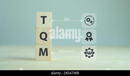 Total Quality Management (TQM) Konzept, TQM auf Holzwürfeln mit Symbolen auf intelligentem Hintergrund, Kopierraum. Managementansatz für langfristigen Erfolg thr Stockfoto