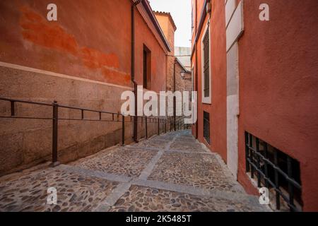 Eine schmale Straße in Segovia mit mittelalterlichen Gebäuden und Steintreppen mit schmiedeeisernen Metallgeländern Stockfoto