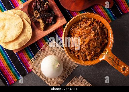 Tinga de Res. Typisch mexikanisches Gericht, das hauptsächlich mit geschreddertem Rindfleisch, Zwiebeln und getrockneten Chilischoten zubereitet wird. Es ist üblich, es auf Maistortilla Tostadas zu servieren Stockfoto