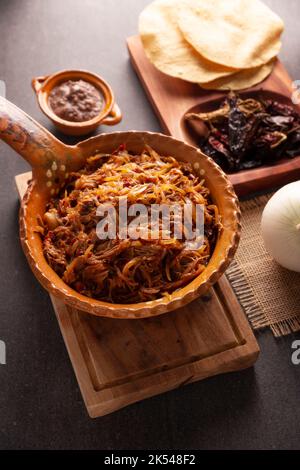 Tinga de Res. Typisch mexikanisches Gericht, das hauptsächlich mit geschreddertem Rindfleisch, Zwiebeln und getrockneten Chilischoten zubereitet wird. Es ist üblich, es auf Maistortilla Tostadas zu servieren Stockfoto