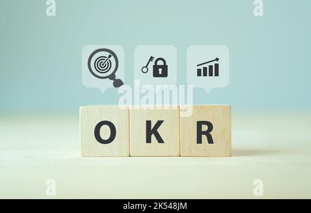 OKR-Text (Ziele, Schlüssel und Ergebnisse) Holzwürfelblock auf grauem Hintergrund. Geschäftsziel und Förderung von Geschäft und Leistung. Konzentriert sich auf gemeinsame goa Stockfoto