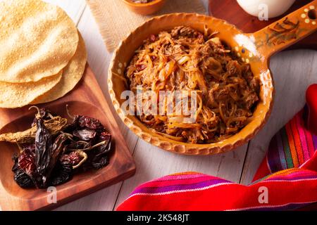 Tinga de Res. Typisch mexikanisches Gericht, das hauptsächlich mit geschreddertem Rindfleisch, Zwiebeln und getrockneten Chilischoten zubereitet wird. Es ist üblich, es auf Maistortilla Tostadas zu servieren Stockfoto