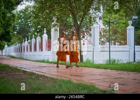 Junge Novizenmönche gehen und plaudern, aufgenommen in Ayutthaya, Thailand, im Mai 2022. Stockfoto