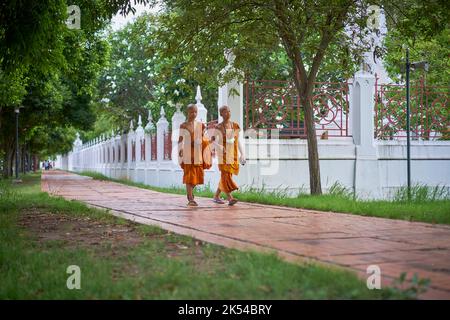 Junge Novizenmönche gehen und plaudern, aufgenommen in Ayutthaya, Thailand, im Mai 2022. Stockfoto