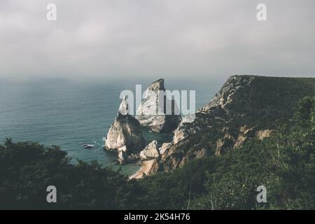 Eine Luftaufnahme von Meeresstapeln am Strand mit bewölktem Hintergrund, Praia da Ursa, Sintra, Portugal Stockfoto