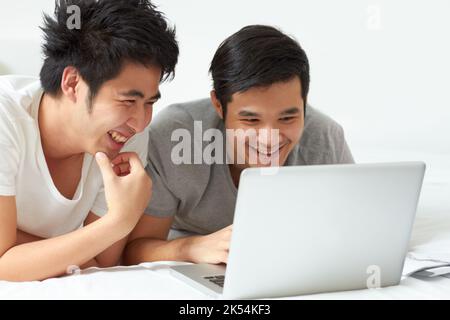 Diese Seite ist fantastisch. Zwei junge Asiaten, die gemeinsam auf einem Laptop im Internet surfen. Stockfoto