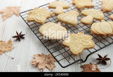 Herbstliches Backen. Kekse in Form von Kürbis und Blättern auf dem Tisch. Gemütliches Herbstkonzept. Stockfoto