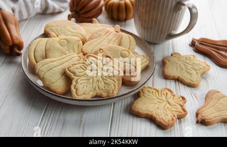 Herbstliches Backen. Kekse in Form von Kürbis und Blättern auf dem Tisch. Gemütliches Herbstkonzept. Stockfoto