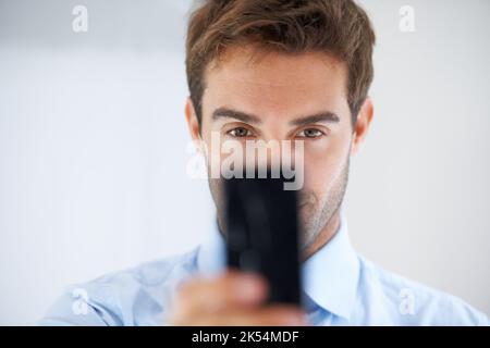 Der perfekte Rahmen. Ein Geschäftsmann hält sein Telefon hoch, um ein Foto zu machen. Stockfoto