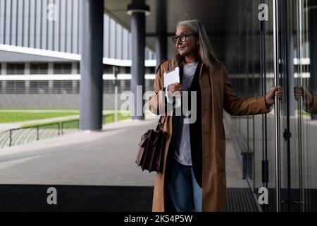 Erfolgreiche ältere Geschäftsfrau tritt in das Business Center ein Stockfoto