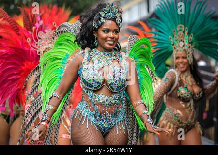 Samba-Tänzerin lächelt in glitzerndem Kostüm mit der Paraiso School of Samba, Notting Hill Carnival, London, Großbritannien Stockfoto