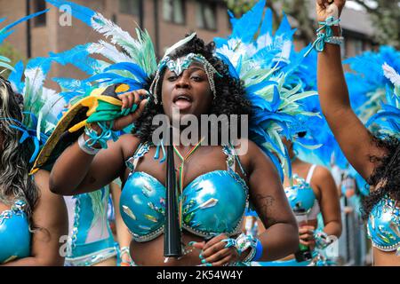 Samba-Tänzerin lächelt in glitzerndem Kostüm mit der Paraiso School of Samba, Notting Hill Carnival, London, Großbritannien Stockfoto