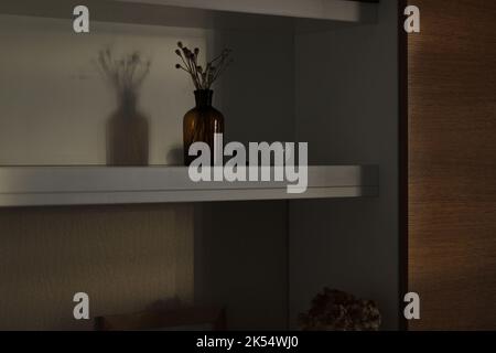 Wohnzimmereinrichtung. Regal mit Dekorobjekten, Vase mit trockenen Blumen, Keramikschale, Rahmen. Design Studio. Stockfoto