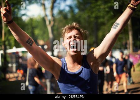 JA. Ein aufgeregt Kerl schreit seine Lungen heraus auf einem Musikfestival. Stockfoto