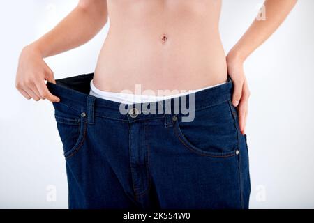 Erreichen ihrer Ziele Gewichtsverlust. Beschnittenes Bild einer Frau, die den Bund ihrer Hose zieht - Weight Loss. Stockfoto