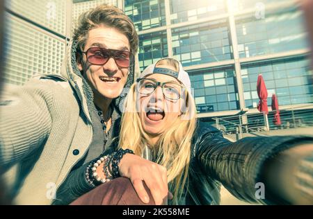 Junges Hipster-Paar in der Liebe nimmt ein lustiges Selfie im städtischen Hintergrund - Alternative Konzept des Spaßes und der Interaktion mit neuen Trends und Technolog Stockfoto