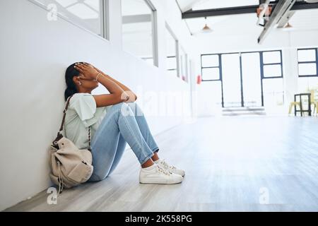 Traurig, Depression und Angst Studentin auf dem Boden in der Universität Campus Klassenzimmer mit Stress für Bildung Stipendium. Depressiv, Burnout und müde Stockfoto