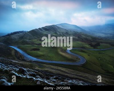 Rushup Edge vom Mam Tor aus gesehen, umhüllt von tief liegender Wolke und Frost, einschließlich einer legendären, gewundenen Straße im Winter Stockfoto