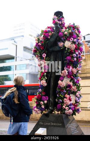 REDAKTIONELLE VERWENDUNG NUR die Sherlock Holmes Statue wird von Netflix mit einer Blumenverjüngungskur ausgestattet, um die Veröffentlichung ihrer neuesten Fortsetzung 'Enola Holmes 2' vor dem Bahnhof Baker Street in London zu feiern. Bilddatum: Donnerstag, 6. Oktober 2022. Stockfoto