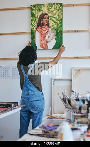 Maler, Künstler und Wandbemalung im Atelier zum Trocknen vor Ausstellung, Verkauf oder Ausstellung. Kunst, kreativ und Frau mit Porträt des Mädchens in Farbe Stockfoto