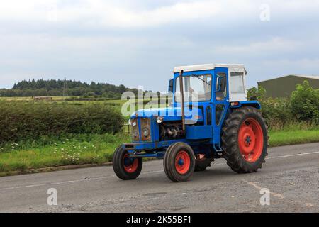 Eastriggs, Schottland - 04. September 2022: Ein alter Fordson Power-Haupttraktor mit Fahrer, der von einem örtlichen Wohltätigkeitslauf zurückkehrt Stockfoto