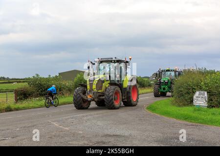 Eastriggs, Schottland - 04. September 2022: Arion-Traktor der Klasse 650, gefolgt von einem John Deere-Traktor, der von einem örtlichen Wohltätigkeitslauf zurückkehrt Stockfoto