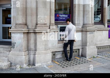 Ein Mann benutzt den Geldautomaten in einer Filiale der NatWest Bank in Camden Town, London, Großbritannien Stockfoto