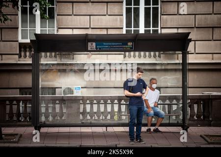 Bild eines weißen kaukasischen älteren Mannes in belgrad, serbien, der in den Straßen von Belgrad, der Hauptstadt Serbiens, auf seinen Bus wartet, während er eine r trägt Stockfoto