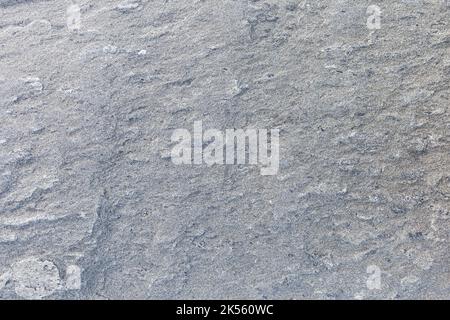 Nahaufnahme einer rauen, hellgrauen Granitfelsoberfläche, Vorderansicht. Abstrakter Vollformat-Hintergrund mit natürlicher Struktur. Stockfoto