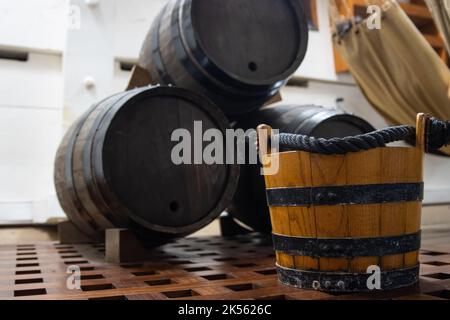 Holzeimer in der Nähe von Pulverfässern im Lagerraum auf dem Kampfschiff Stockfoto